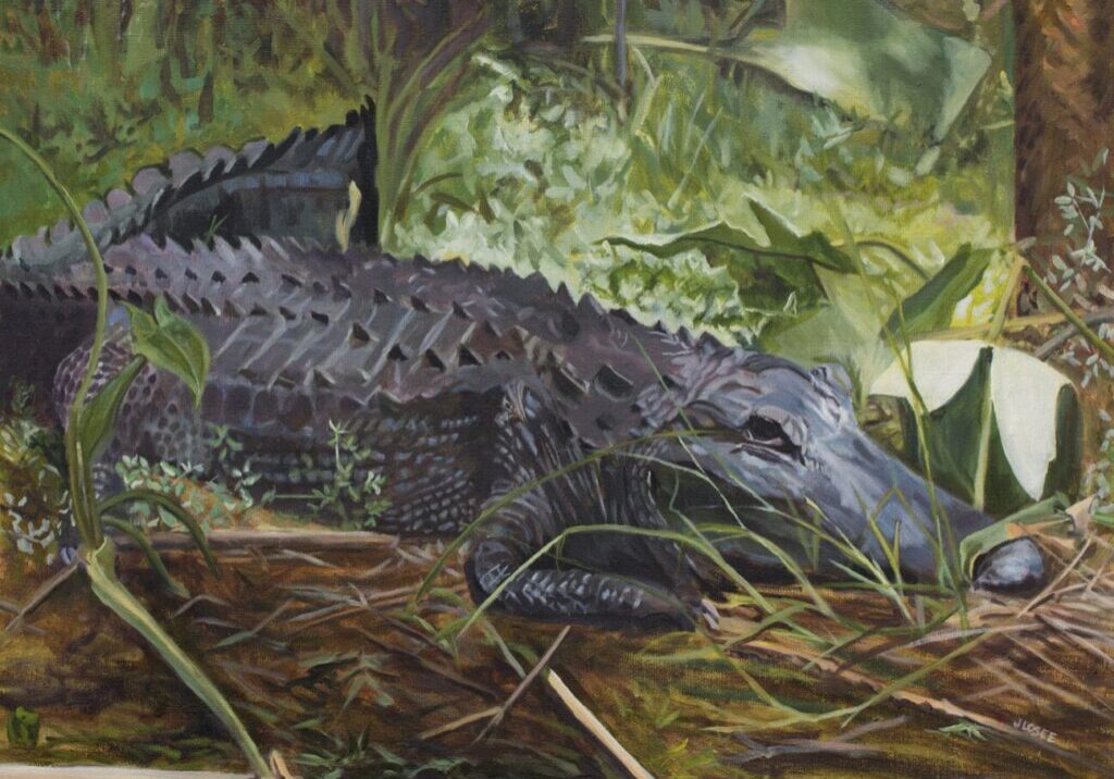 Crocodile resting in lush green foliage.