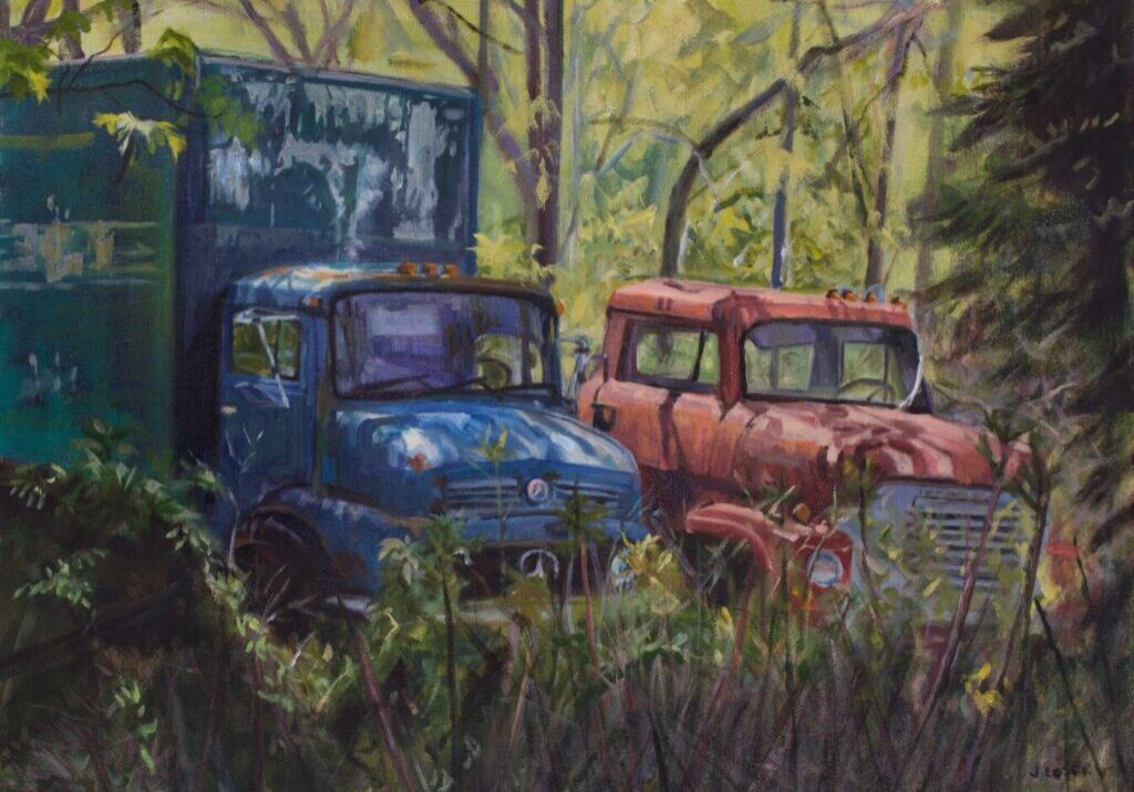 Two old trucks in a forest setting.
