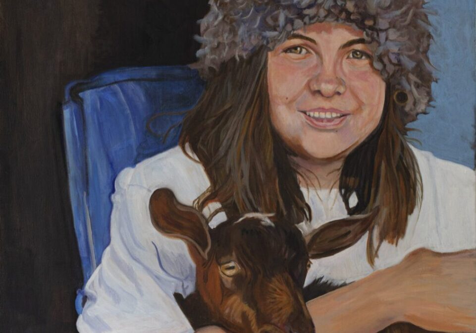 Person with furry hat holding a goat.